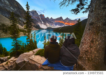 Lake Moraine Sunrise with Tourists Overlooking Blue Water and Majestic Mountains 134973581