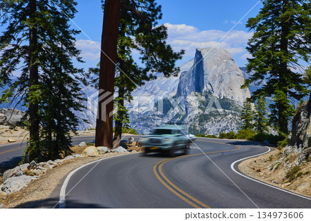 Yosemite Mountain Road Curve with Moving Car and Half Dome in Summer 134973606