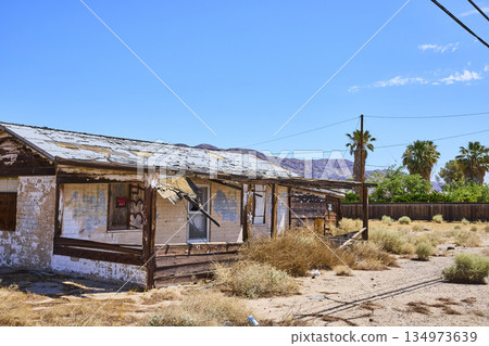 Abandoned Desert House With Faded Wood Porch Palm Trees And Distant Mountains Abandoned Desert House With Faded Wood Porch Palm Trees And Distant Mountains 134973639