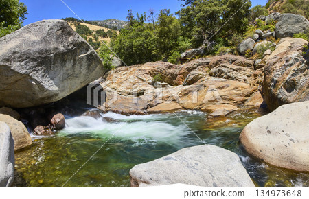 River Pool and Granite Boulders with Lush Greenery in Sunlit California Landscape 134973648