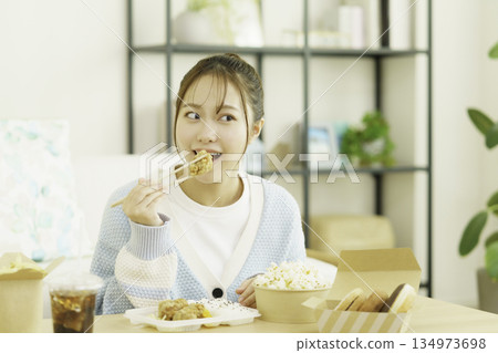 Young Japanese woman eating bento in the living room Young Japanese woman eating bento in the living room 134973698