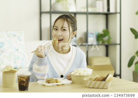 Young Japanese woman eating bento in the living room Young Japanese woman eating bento in the living room 134973699