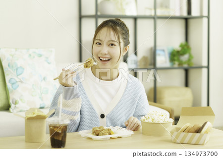 Young Japanese woman eating bento in the living room Young Japanese woman eating bento in the living room 134973700