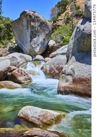 Granite Boulders and Turquoise Water Along Mountain River in Sunlit Wilderness 134973779
