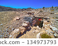Abandoned Mine Entrance in Desert Landscape With Rocky Terrain and Distant Mountains 134973793