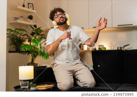 Arabian man plays air guitar dances rock n roll seated laughs energy fun music night indoors excited 134973995