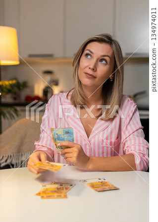 Adult woman counts cash euros sorts budget piles expenses savings plans family finance night budget Adult woman counts cash euros sorts budget piles expenses savings plans family finance night budget 134974011