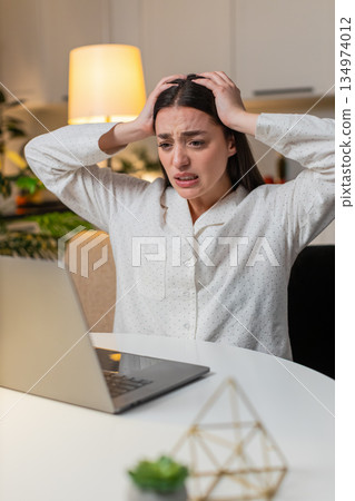 Young woman at night home plays online game on laptop lose from online game or lottery feels upset 134974012