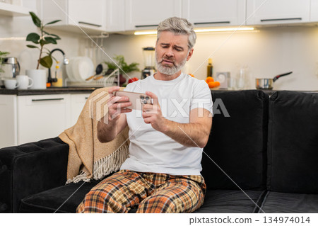 Middle-aged man loses online game on smartphone reacts to lottery app result hits retry sighs sadly 134974014