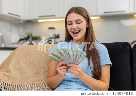 Young woman counts dollars cash money plans big purchase feels proud of savings salary and bonus Young woman counts dollars cash money plans big purchase feels proud of savings salary and bonus 134974018
