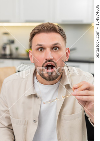 Young man removes glasses says wow happy and surprised after good news with bright smile wide eyes 134974038