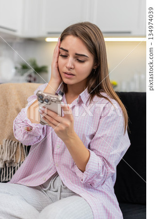 Young woman upset by game loss and job refusal sighs touches brow shakes head no holding smartphone Young woman upset by game loss and job refusal sighs touches brow shakes head no holding smartphone 134974039