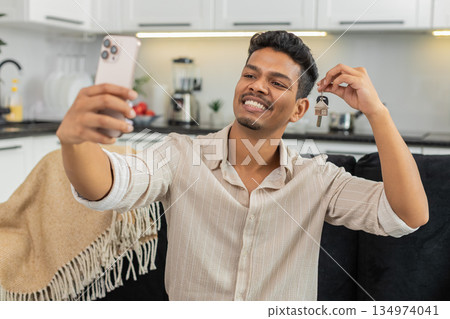 Indian man holds house key keychain smiles takes smartphone selfie keys posts on social media proud Indian man holds house key keychain smiles takes smartphone selfie keys posts on social media proud 134974041