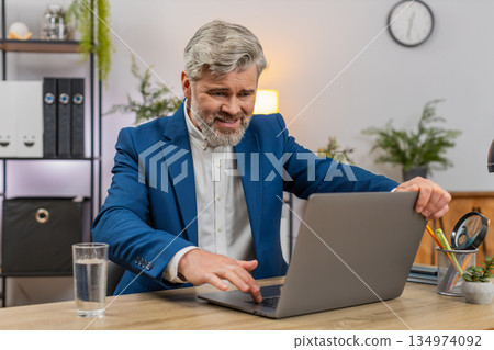 Middle-aged businessman fumes at laptop frozen error closes lid sighs disappointed frustration shows 134974092