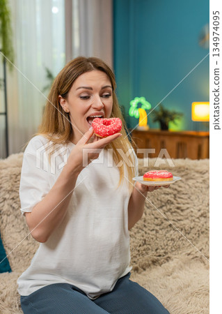Pregnant woman bites pink donut laughs enjoys sweet treat keeps fun memory forever Pregnant woman bites pink donut laughs enjoys sweet treat keeps fun memory forever 134974095