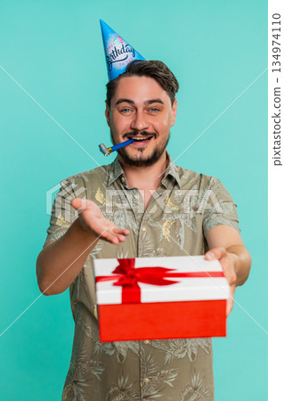 Adult man in party hat smiling happily giving birthday gift to someone celebrating event generosity 134974110