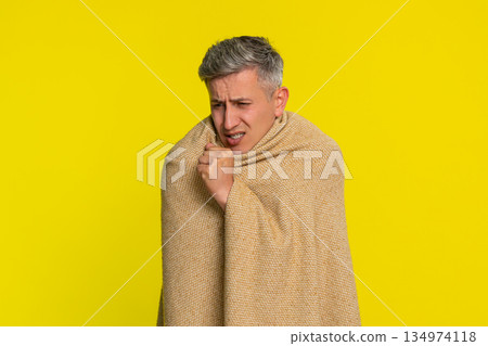 Adult man wrapped in blanket coughing with tired sick face showing flu symptoms cold virus illness 134974118