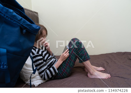Child in pajamas using a smartphone on the bed. Young boy focused on a mobile device 134974226