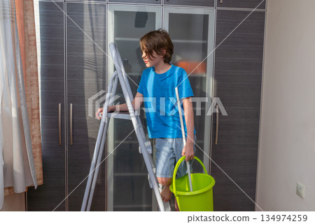 Young boy helping with household chores. Child on a stepladder with a cleaning bucket 134974259