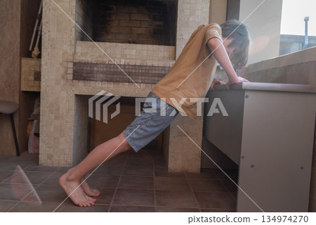 Young boy doing incline push-ups at home. Child strength training workout 134974270