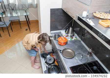 Person searching in a messy kitchen drawer for a pot. High angle view of domestic life Person searching in a messy kitchen drawer for a pot. High angle view of domestic life 134974282
