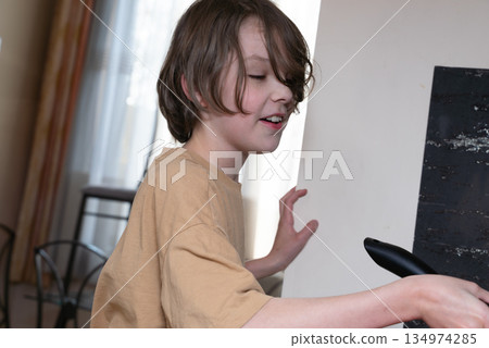 Young boy learning to cook in the kitchen. Candid portrait of a child doing household chores 134974285