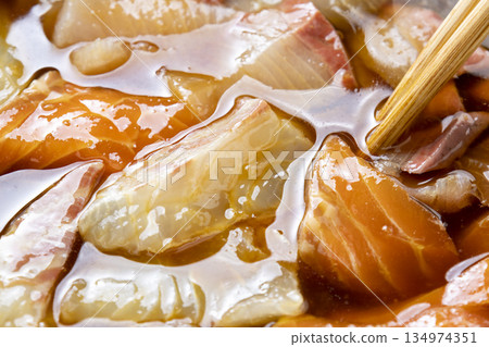 A cooking scene where raw fish fillets (sea bream, yellowtail, salmon) are marinated in a marinade. 134974351