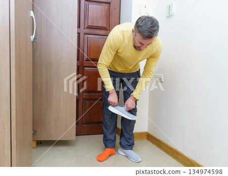 Man with mismatched socks putting on shoes in a home entryway. Getting ready for the day Man with mismatched socks putting on shoes in a home entryway. Getting ready for the day 134974598