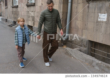 Father and son walking hand in hand on a city street. Family bonding outdoors 134974614