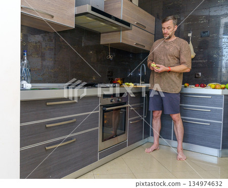 Man preparing a healthy apple snack. Domestic lifestyle in a modern kitchen 134974632