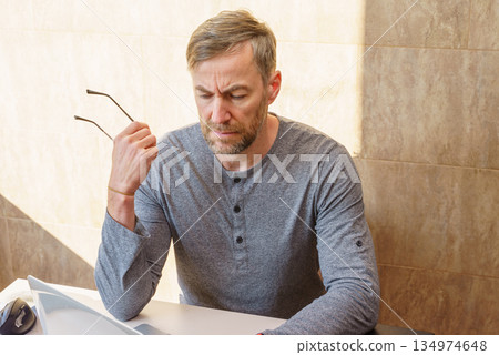 Focused middle-aged man with a pensive expression working at his desk. Stress and burnout concept Focused middle-aged man with a pensive expression working at his desk. Stress and burnout concept 134974648