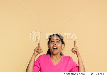 Indian woman seriously pointing finger upwards, indicating important message or announcement above 134974761