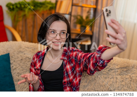 Blogger woman filming vlog stream on smartphone camera at home smiling and interacting with audience 134974788