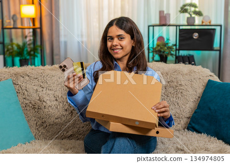 Indian woman ordering fast food online on smartphone credit card and happy of fast delivery at home Indian woman ordering fast food online on smartphone credit card and happy of fast delivery at home 134974805