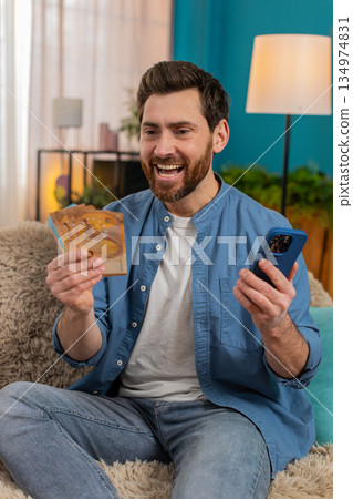 Man checking balance on smartphone, excited about received money, celebrating lottery or game win Man checking balance on smartphone, excited about received money, celebrating lottery or game win 134974831