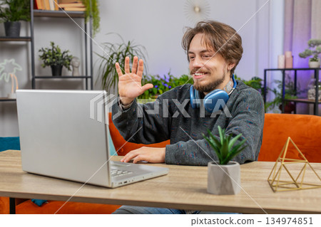 Man sitting on home couch, looking at camera, making video conference call with friends or family 134974851