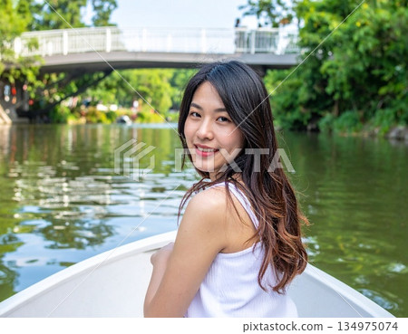 一位美麗的年輕亞洲女子在公園的池塘上划船 134975074