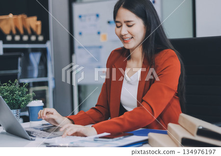 Asian business woman working on a laptop in a professional office Asian business woman working on a laptop in a professional office 134976197