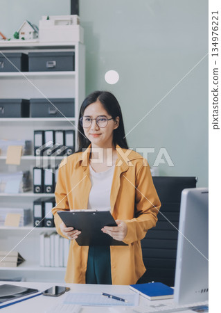Business woman using calculator for do math finance on wooden desk in office and business working background, tax, accounting, statistics and analytic research concept. 134976221
