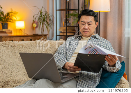 Stressed man freelancer feeling worried about financial problem doing paperwork sitting on sofa 134976295