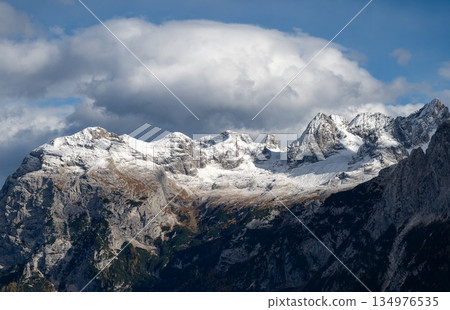 Snow-dusted Dolomites mountain ridge beneath dramatic clouds and blue sky 134976535