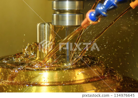 Close up scene the CNC milling machine finishing cut the brass shell mold parts with oil coolant method. 134976645