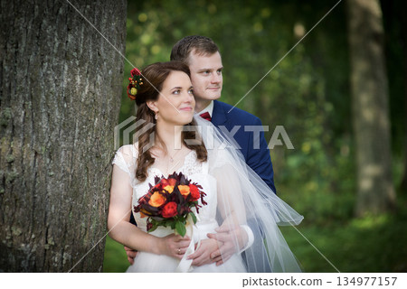 Romantic Bride And Groom Embracing By Tree Romantic Bride And Groom Embracing By Tree 134977157