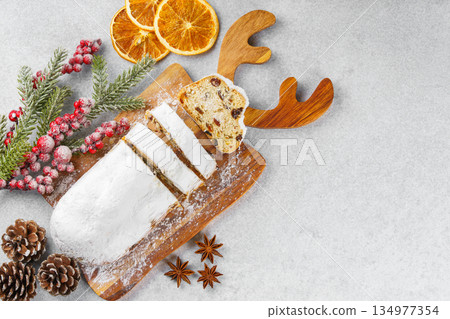 Traditional sliced Christmas stollen loaf with raisins and powdered sugar on wooden cutting board 134977354