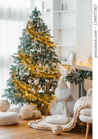 Elegant white Scandinavian interior with decorated Christmas tree with lights and winter home decor Elegant white Scandinavian interior with decorated Christmas tree with lights and winter home decor 134977367