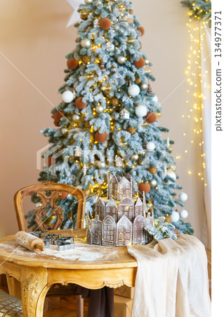 Beautiful decorated Christmas tree with ornaments and table with dough for baking gingerbread cookie 134977371