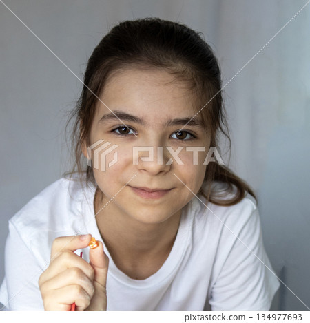 Portrait of a cheerful girl holding a small candy, showing calm and gentle youthfulness 134977693