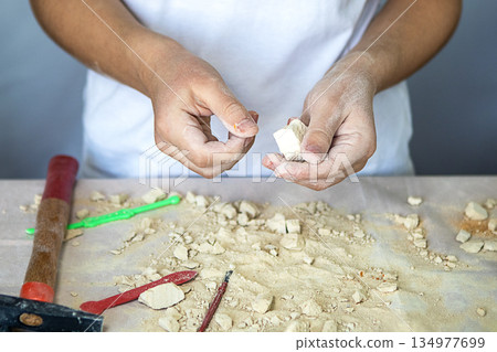 A baker shapes dough by hand on a floury table with pastry tools A baker shapes dough by hand on a floury table with pastry tools 134977699