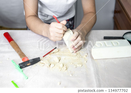 Child at craft table carving soap block with tools and shavings for a creative project 134977702