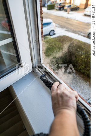 Cleaning the window. A man with steam device removes dirt from the plastic window frame. 134978134